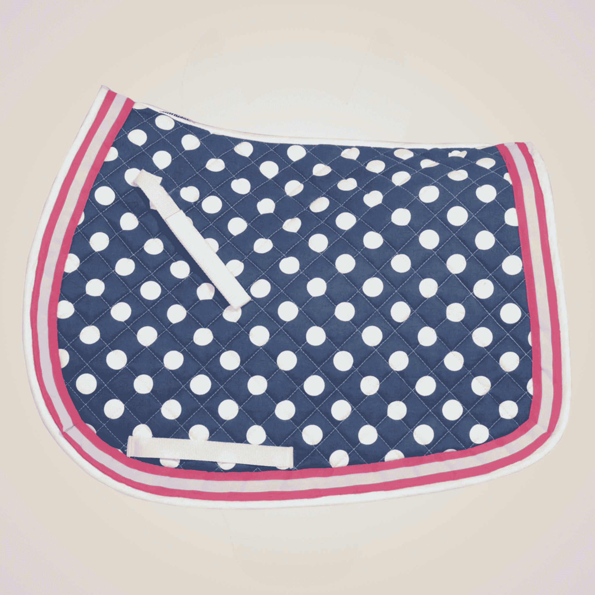 Navy blue saddle pad with white polka dots and pink border on a beige background