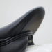 Close-up of a black leather saddle on a white background