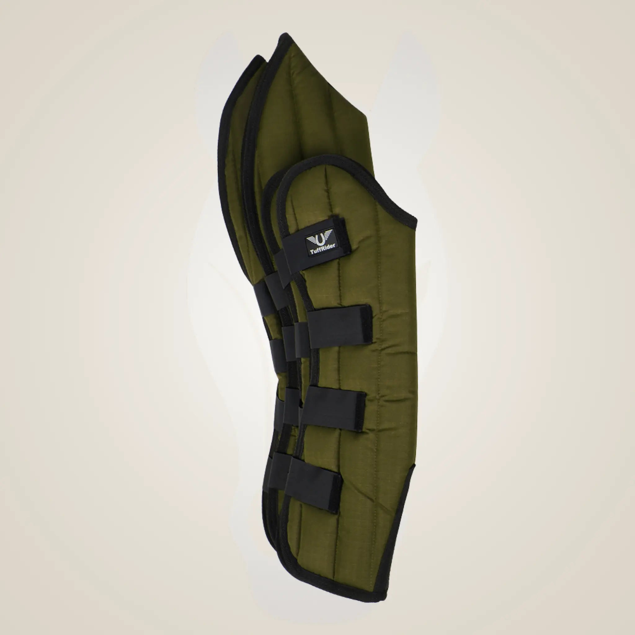 Green equestrian leg guard with black straps on a beige background