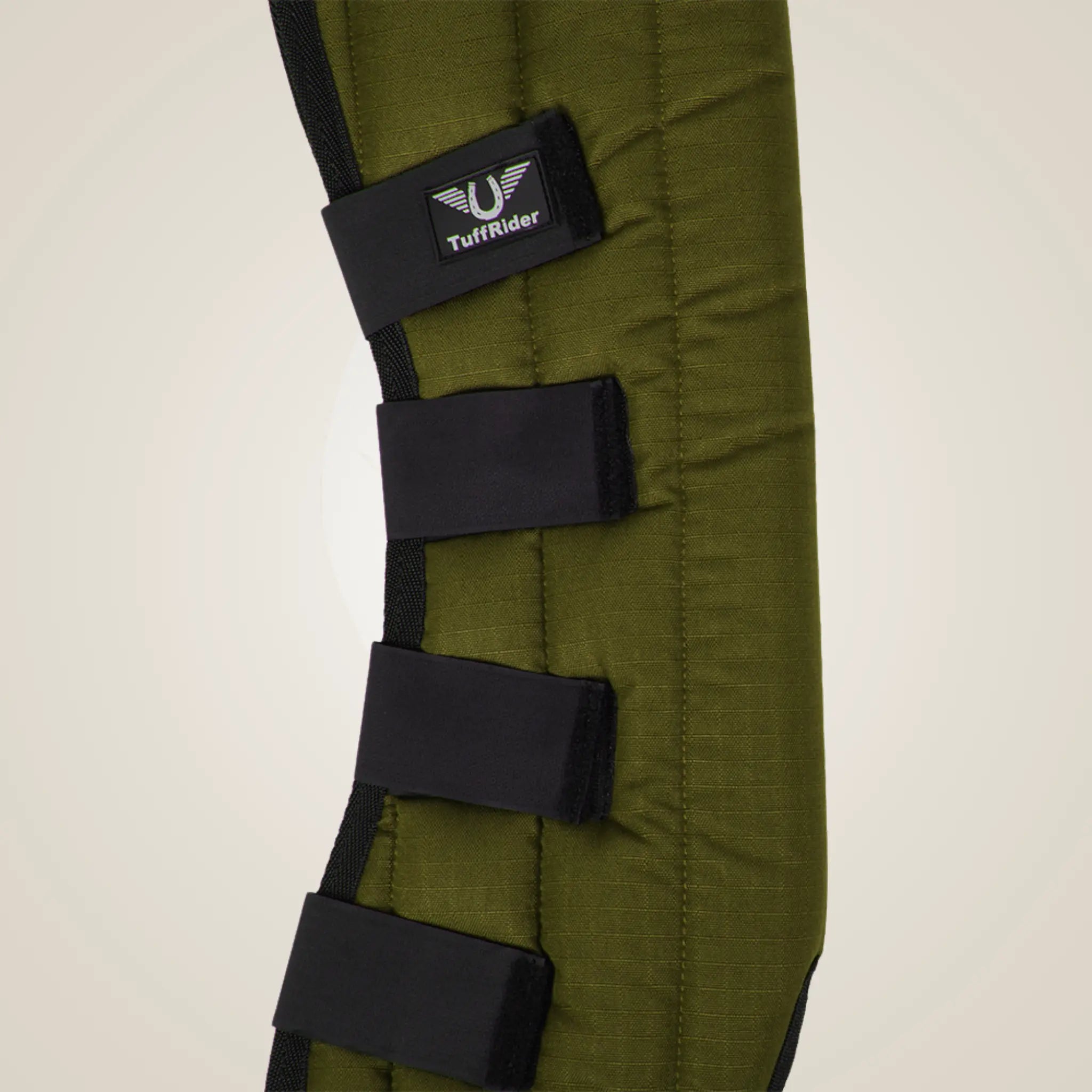 Green protective pad with black straps and TuffRider logo on a beige background